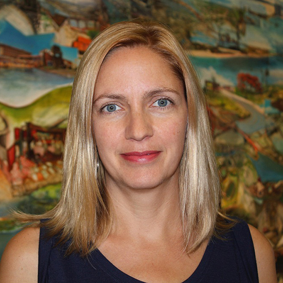 Headshot of a woman with long blonde hair in front of a painted scene